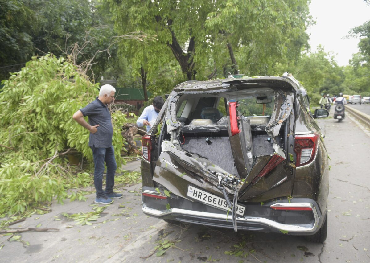 On Monday, May 30, 2022, a car was damaged after an uprooted tree fell due to a dust storm accompanied by rain in New Delhi at Ashoka Road.